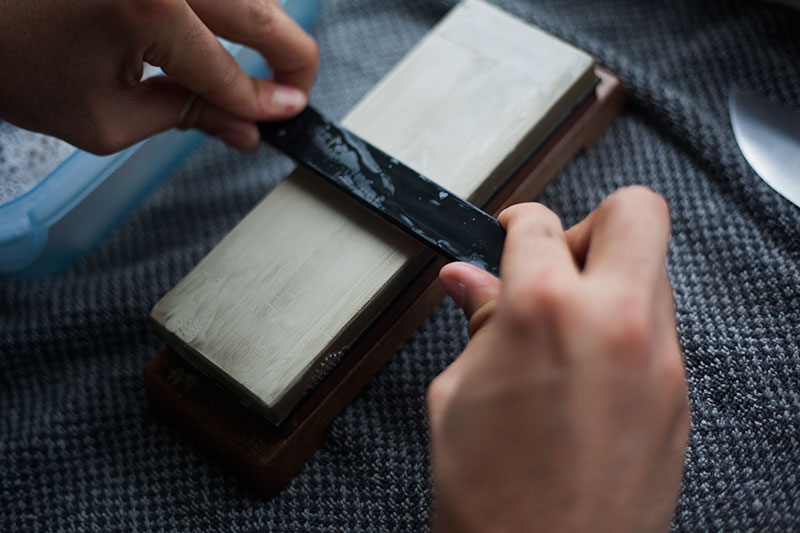 using a whetstone to sharpen the edge of a knife